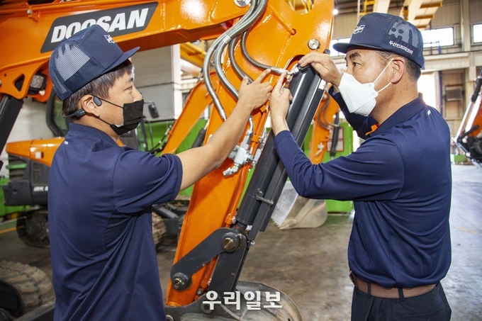 대한민국 명장 김주호 기술부장(우)이 현대두산인프라코어 인천공장에서 후배에게 기술을 전수하고 있다.