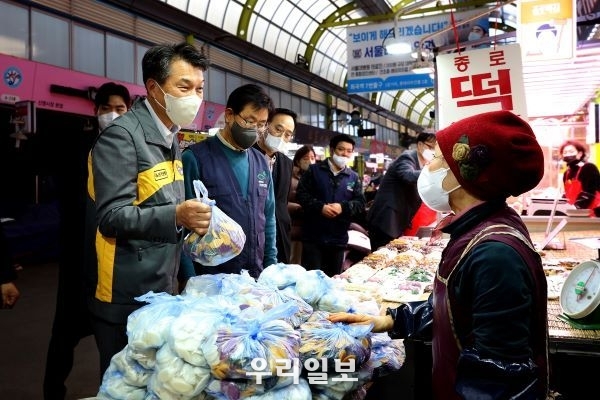 11일 서울시 양천구에 위치한 신영시장에서 열린 설날맞이 '전통시장 사랑나눔 행사'에서 성채현 KB국민은행 영업그룹 부행장이 떡을 구입하고 있다.