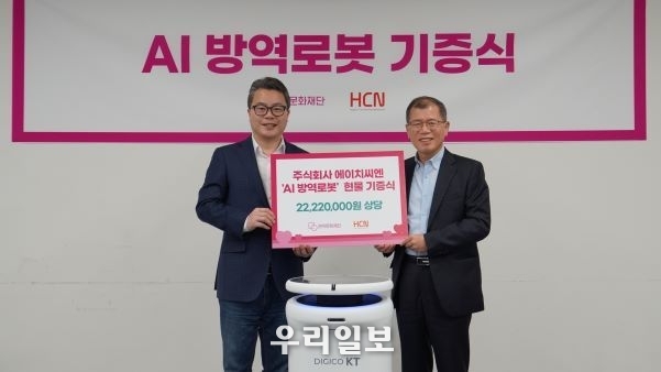 지난 13일 HCN 조석봉 상무(오른쪽)이 관악문화재단 차민태 대표(왼쪽)에게 KT AI방역로봇 현물 기증식을 갖고 기념촬영을 하고 있다.
