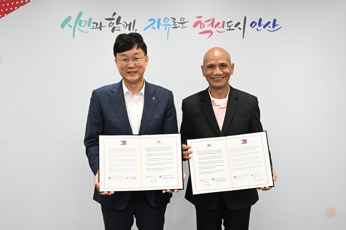 이민근 안산시장(왼쪽)이 필리핀 산페르난도시 헤르메네질도 구알베르토(Hermenegildo A. Gualberto) 시장과 협약서를 들고 기념촬영을 하고 있다.ⓒ안산시 제공