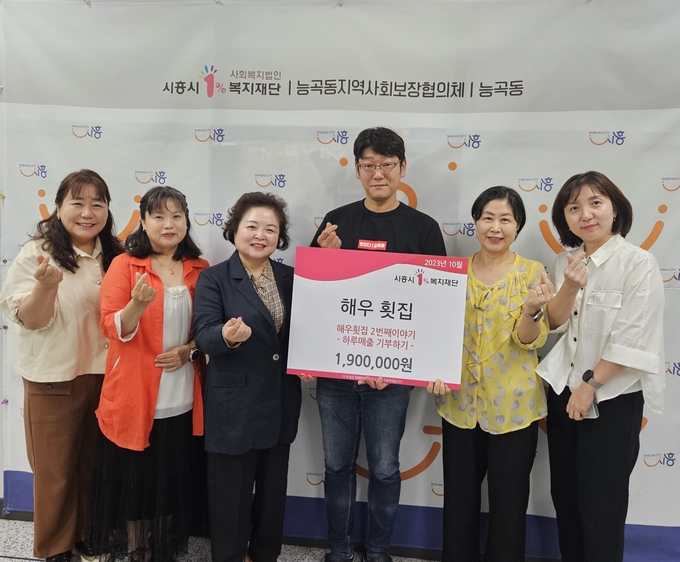 시흥시 능곡동 해우횟집이 하루 매출 기부에 동참하고 기념촬영을 하고 있다.ⓒ시흥시 제공