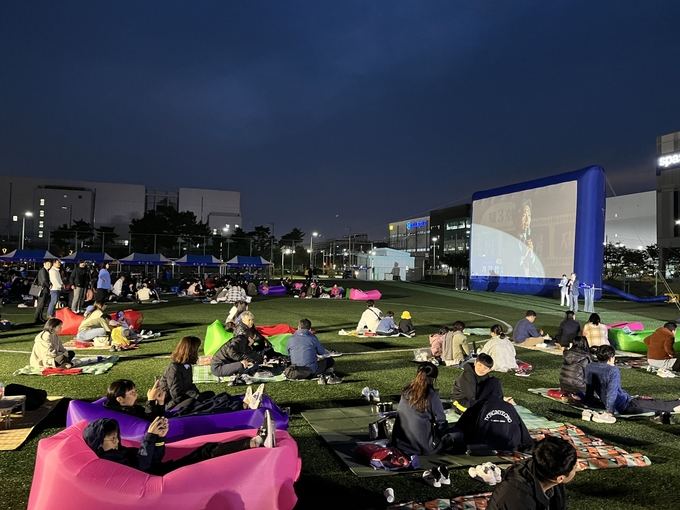 지난 6일 저녁 인천공항 물류단지 내 체육공원에서 열린 제3회 가을밤 자유무역지역 영화제 에서 인천공항 물류기업 상주직원 및 가족들이 인기영화 콘크리트 유토피아 를 관람하고 있다. ⓒ 인천국제공항공사 제공
