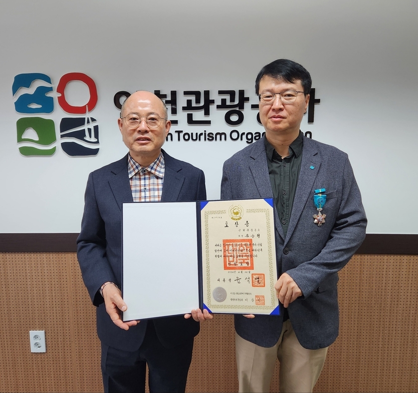 인천관광공사 백현사장이 직원 중 중증 장애인 유승형 차장에게 2024년 장애인고용촉진대회에서 산업포장을 수상하고 있다. ⓒ 인천관광공사 제공