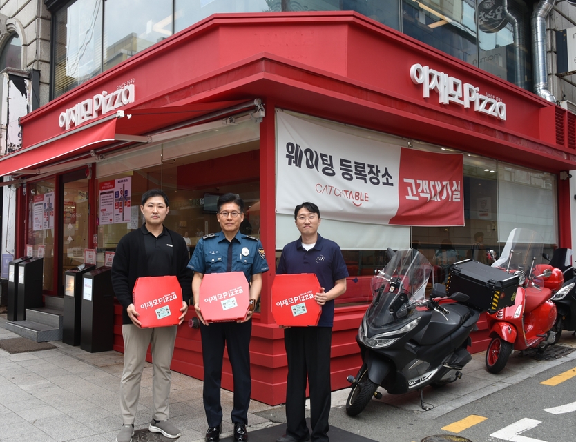 “심태환 부산중부경찰서장과 김익태 이재모피자 대표 등 관계자들이 보이스피싱 예방 문구가 부착된 피자 박스를 들고 기념촬영을 하고 있다.” ©우리일보