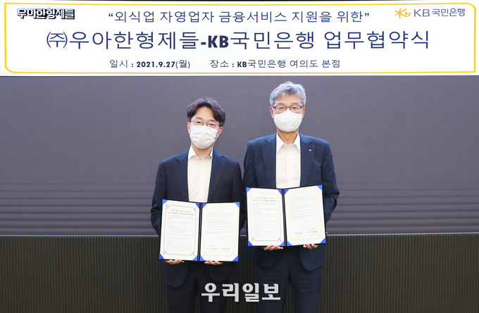 27일 KB국민은행 여의도 본점에서 열린 외식업 자영업자 금융서비스 지원을 위한 KB국민은행-(주)우아한형제들 업무 협약식에서 (오른쪽)허인 KB국민은행장과 (왼쪽)김범준 우아한형제들 대표이사가 업무협약을 체결하고 기념촬영을 하고 있다.