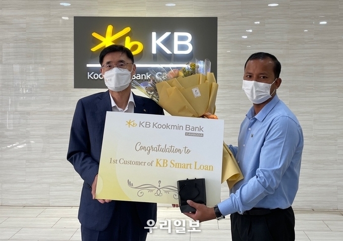 (왼쪽)김현종 KB국민은행 캄보디아법인장이 KB스마트론 1호 고객과 기념촬영을 하고 있다.