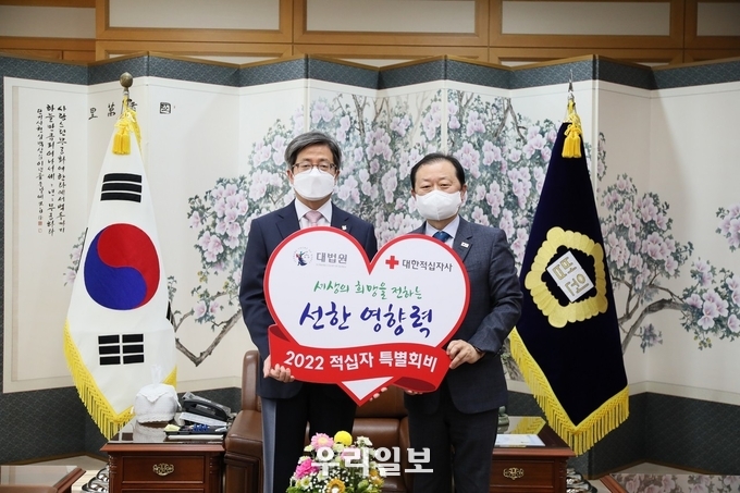  김명수 대법원장(사진 왼쪽)이 12월 17일(금), 오전 11시 서울 서초구 대법원장 집무실에서 대한적십자사 신희영 회장(사진 오른쪽)에게 2022년도 적십자 특별회비를 전달했다.