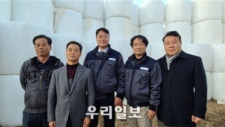 왼쪽부터 밀양시 대곡리 윤효근 이장, 윤충근 사장, ㈜에이티랩 김도훈 대표, 신현정 연구소장, ㈜굿콜 이원중 회장이 마당에 쌓아 둔 유황 볏짚 앞에서 기념촬영을 하고 있다.