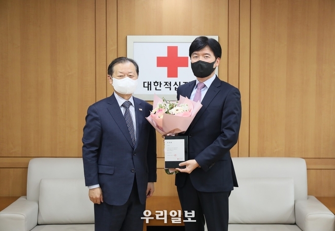 시인 강원석(사진 오른쪽)이 1. 10(월) 14시, 서울 중구 대한적십자사 서울사무소에서 신희영 대한적십자사 회장(사진 왼쪽)으로부터 홍보대사 위촉패와 꽃다발을 받았다. 