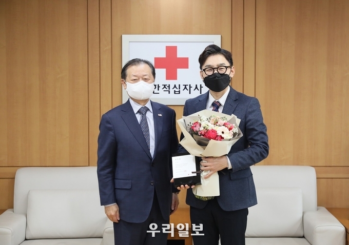 가수 추가열(사진 오른쪽)이 1. 10(월) 14시, 서울 중구 대한적십자사 서울사무소에서 신희영 대한적십자사 회장(사진 왼쪽)으로부터 홍보대사 위촉패와 꽃다발을 받았다. 